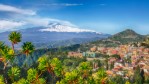 Roofs of a lot of buldings. Smoking snow-capped Mount Etna volcano. Taormina, Sicily, Italy