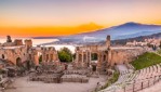 The Greek Theater of Taormina as the Sun sets behind the smoking Etna, creating the beautiful colors