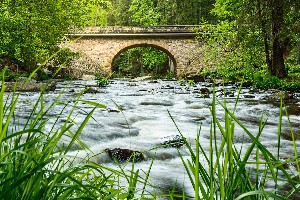 View of the stone bridge Zemská brána and a mountain river in the woods