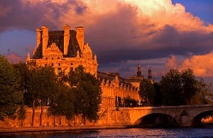 Historická budova muzea Louvre v Paříži je osvětlena teplým světlem zapadajícího slunce